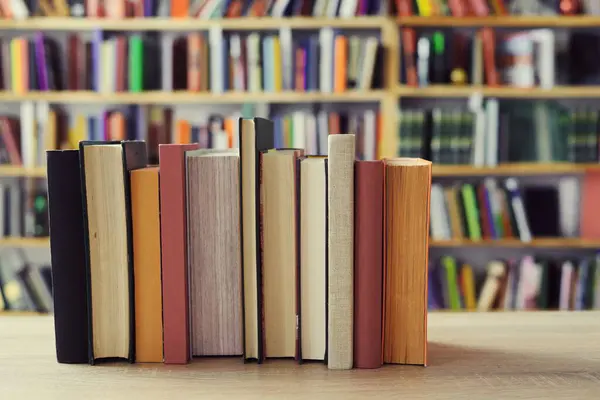 stack books in library. stack of old books. Paper publications from the old library. Dark background.Old books in vintage library. History, education concept. Hand reaches for and pulls classic book from library shelf; vintage look.