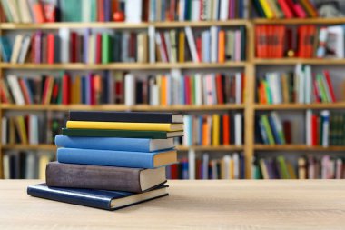 Kitaplar ahşap masa üzerinde kütüphane arka planında