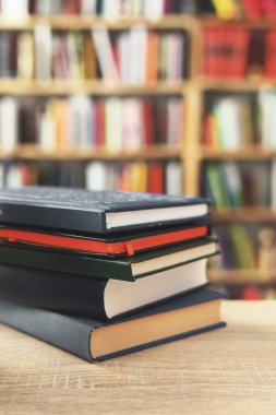 Kütüphanedeki ahşap masada yığınla kitap.