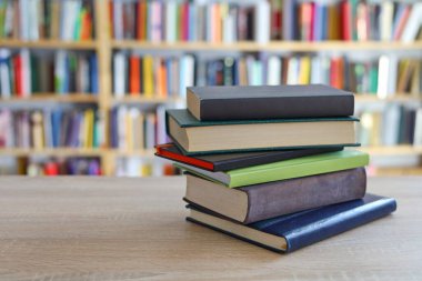 Duvara karşı ahşap bir masada yığınla kitap..