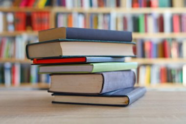 Kütüphanedeki ahşap masada yığınla kitap.