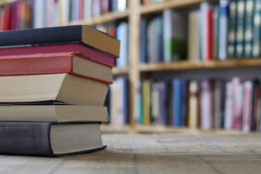 Kütüphanedeki masanın üzerinde yığınla kitap, kütüphanedeki ahşap masa, eğitim, okul,