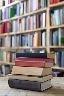 Kütüphanedeki ahşap bir masada yığınla kitap.