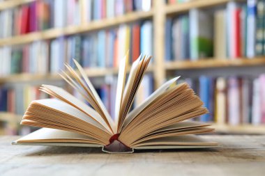 Kütüphanedeki ahşap masada yığınla kitap.