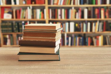 Ahşap masanın üzerinde bulanık arka plana karşı bir yığın kitap. Okula geri dön.