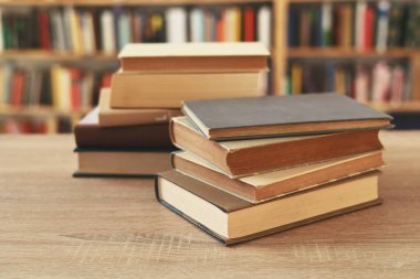 Tahta masanın üzerinde bir yığın kitap. Kütüphane, kütüphanenin arka planına karşı kitap yığını, kütüphanenin önündeki kitap yığını, ahşap masa üzerindeki kitaplar, eğitim, yüksek kaliteli kitap fotoğrafçılığı, En İyi Kitap Fotoğrafı, ünlü yazarları okuduk.
