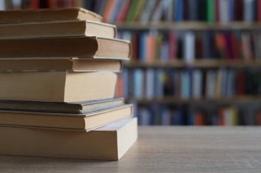 Ahşap masanın üzerinde bulanık arka plana karşı bir yığın kitap. Metin için boşluk