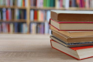 Kütüphanedeki ahşap masada yığınla kitap.
