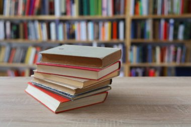 Kütüphanedeki ahşap masada yığınla kitap.