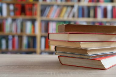 Kütüphanedeki ahşap masada yığınla kitap.