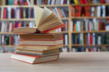 Kütüphanedeki masanın üstünde bir yığın kitap var.