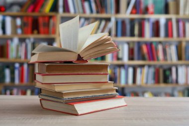 Kütüphanedeki ahşap masada yığınla kitap.