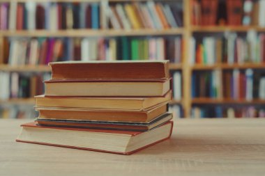 Kütüphanedeki ahşap masada yığınla kitap.