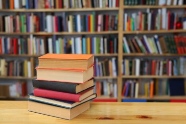 Kütüphanedeki ahşap masada yığınla kitap.