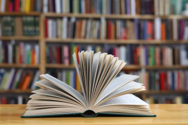 Kütüphanedeki ahşap masada yığınla kitap.
