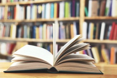 Açık kitap, ahşap masadaki kitaplar, kütüphane arka planı. Eğitim ve okul kavramına geri dönüş. Açık sayfalı kitap, kapatma, okul raflarında kitaplar, ahşap masa üzerinde açık kitap. Okul konseptine geri dönüş, yüksek kaliteli kitap fotoğrafçılığı., 