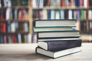 Kütüphanedeki ahşap masada yığınla kitap.