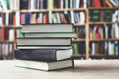 Kütüphanede ahşap arka plan üzerine bir yığın kitap, düzgünce düzenlenmiş kitaplar. Kütüphanelerdeki rafların çoğunda kitabın omurgasında (numaralar, kodlar veya etiketler) net işaretler bulunan boy, konu veya türe göre düzenlenmiş kitaplar vardır. Kütüphaneler sessiz yerlerdir.