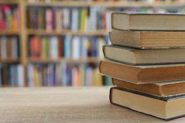 Kütüphanede masanın üzerinde bir yığın kitap, eğitim konsepti.