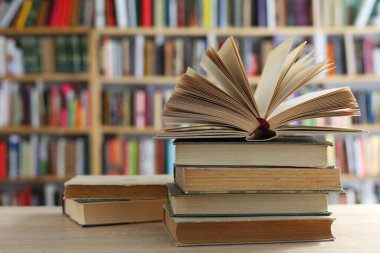 Kütüphanedeki ahşap masada yığınla kitap.