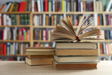 Arka plandaki masanın üzerinde bir yığın kitap var.