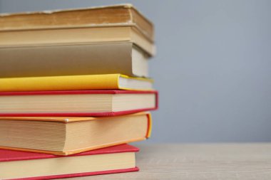 Bulanık arka plana karşı ahşap masadaki kitap yığını