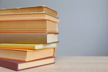 Kütüphanede, ahşap bir masanın üzerinde yığınla kitap..