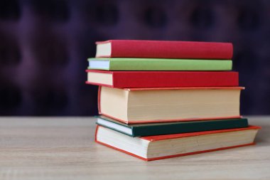 Bulanık arkaplanda ahşap masa üzerinde kitap yığını