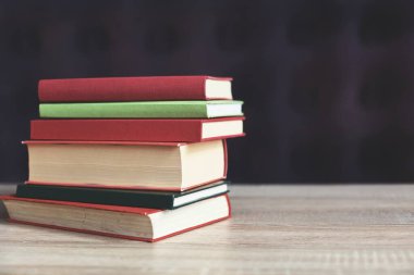 Masadaki kitap yığını tuğla duvar arkaplanına karşı