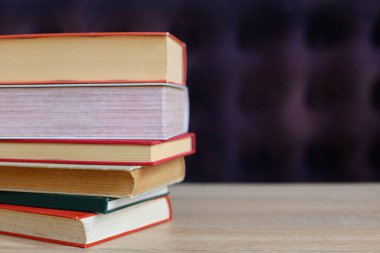 Bulanık duvara karşı ahşap masadaki kitap yığını