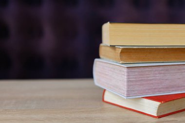 Ahşap masanın üzerinde bir yığın kitap ve kırmızı kitaplar.