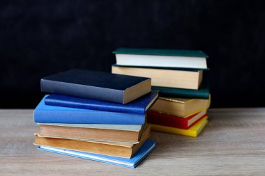 Siyah ahşap masada yığınla kitap.