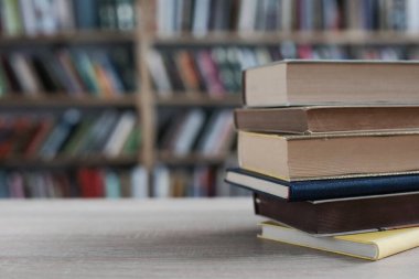 Ahşap masanın üzerinde bulanık arka plana karşı bir yığın kitap. Metin için boşluk