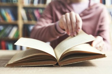 Kadın kütüphanede kitap okuyor.