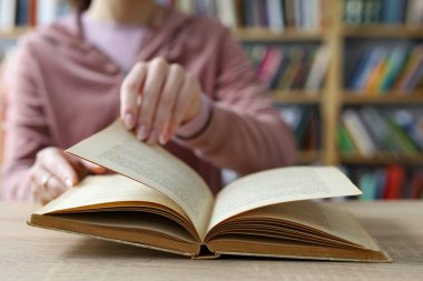 Kadın kütüphanede kitap okuyor.