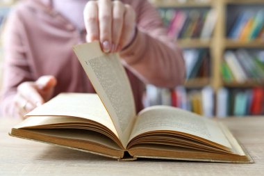 Kadın kütüphanede kitap okuyor.