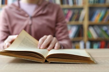 Kadın kütüphanede kitap okuyor.