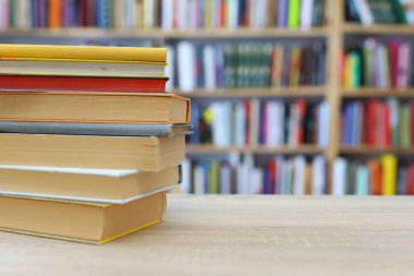 Arka plandaki ahşap masada bir kütüphanede kitaplar.