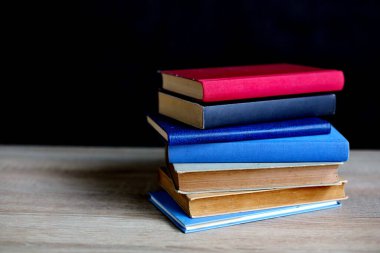 Siyah arka plan üzerine bir yığın kitap, düzgünce düzenlenmiş kitaplar. Kütüphanelerdeki rafların çoğunda kitabın omurgasında (numaralar, kodlar veya etiketler) net işaretler bulunan boy, konu veya türe göre düzenlenmiş kitaplar vardır. Kütüphaneler sessiz yerlerdir.