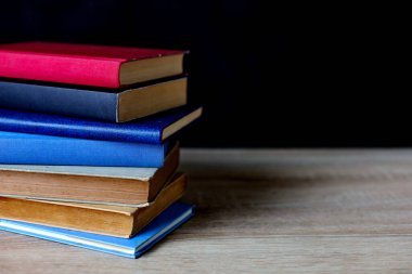 Siyah arka plan üzerine bir yığın kitap, düzgünce düzenlenmiş kitaplar. Kütüphanelerdeki rafların çoğunda kitabın omurgasında (numaralar, kodlar veya etiketler) net işaretler bulunan boy, konu veya türe göre düzenlenmiş kitaplar vardır. Kütüphaneler sessiz yerlerdir.