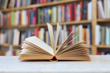 Kapaklı kitaplarla dolu açık bir kitap, arka planda masa. Okula dönüyorum. Boşluğu kopyala.