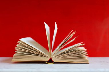 Ahşap bir arka planda kırmızı kurdeleli açık bir kitap.