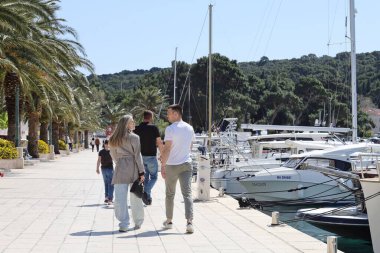 Makarska, Hırvatistan, 13.04.2025. Makarska rıhtımında turistler güneşli bir günde, liman ve yat limanında yürüyorlar.