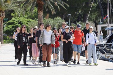 Makarska, Hırvatistan, 13.04.2025. Makarska rıhtımında turistler güneşli bir günde, liman ve yat limanında yürüyorlar.