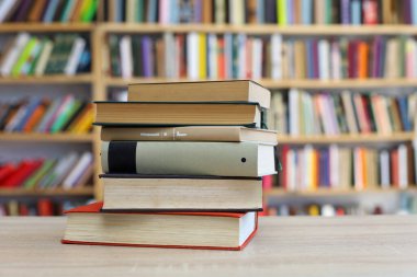 Kütüphanedeki ahşap masada yığınla kitap.