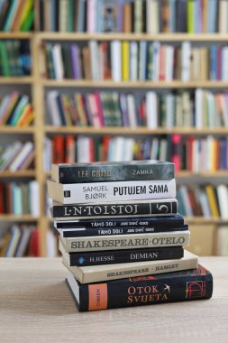 Vrgorac, Hırvatistan, 17.04.2025. Kütüphanede kitapları olan genç bir kütüphaneci, kütüphanedeki ahşap masada kitaplar.