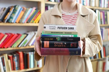 Vrgorac, Hırvatistan, 17.04.2025. Kütüphanede kitapları olan genç bir kütüphaneci, kütüphanedeki ahşap masada kitaplar.