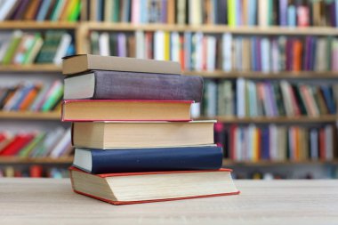 Kütüphanedeki ahşap masada yığınla kitap.