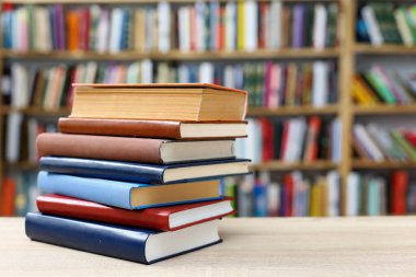 Kütüphanedeki ahşap bir masada yığınla kitap..