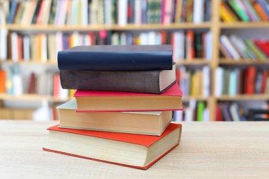 Kütüphanedeki ahşap masada yığınla kitap.